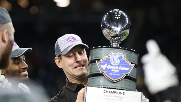 Western Michigan celebrating a Quick Lane Bowl victory with the trophy.